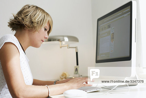 Young woman using desktop computer  side view