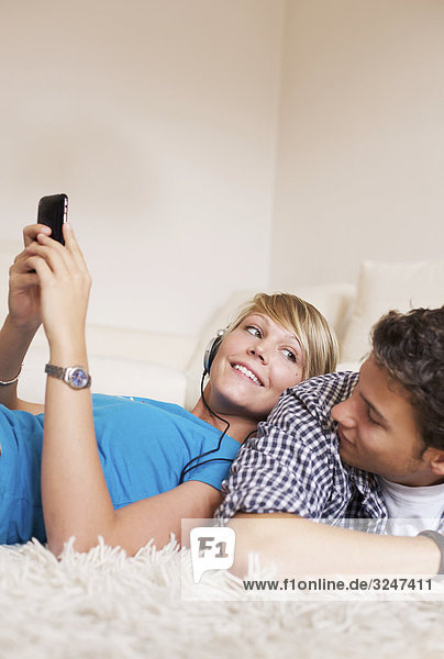 Teenager couple lying on carpet and listening to music  low-angle view