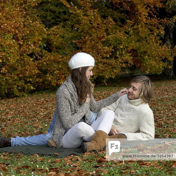 A young couple sitting together in a park  Skane  Sweden.
