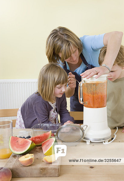 Junge  Mädchen und Mutter  die Fruchtsmoothies machen.