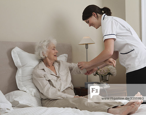 Krankenschwester rollt den Ärmel einer älteren Frau hoch.