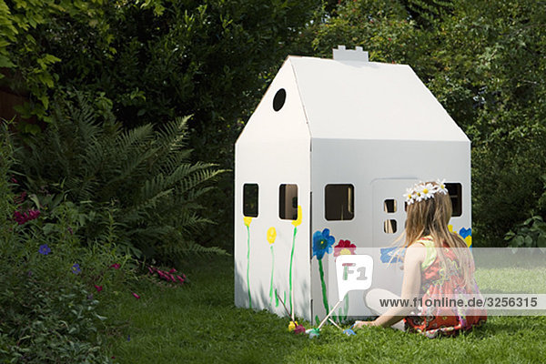 Ein Mädchen  das ein Haus aus Pappe malt.