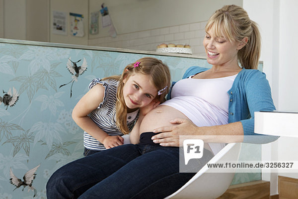 Eine junge schwangere Mutter mit ihrer Tochter
