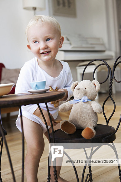 Kleinkind mit seinem Teddy auf der Teeparty