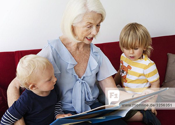 A grandmother reading to two toddlers