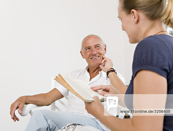 woman reading book to senior man