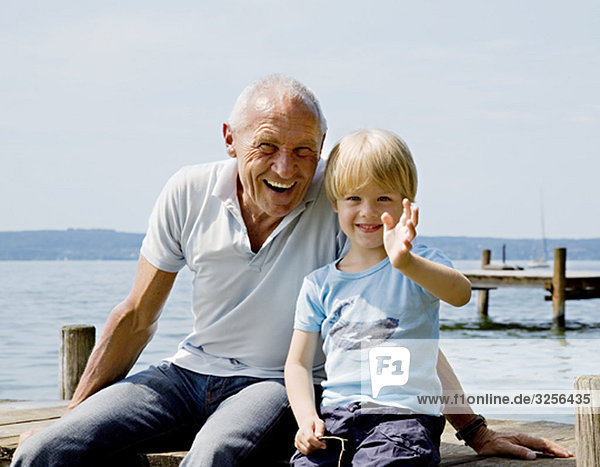 boy with grandfather on pier at lake