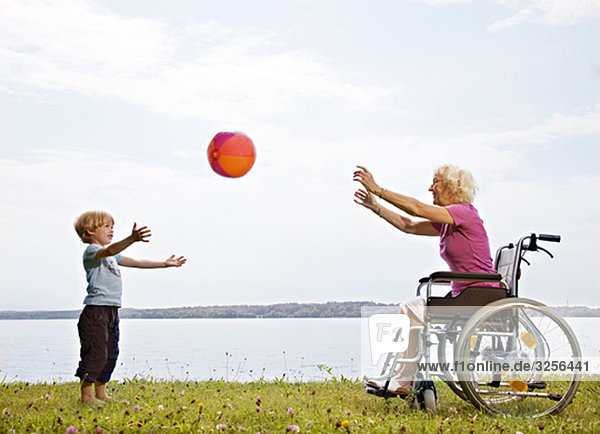 Junge spielt Ball mit älterer Frau