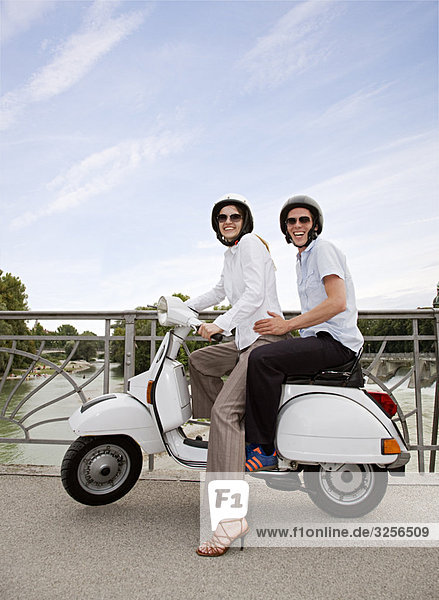 couple on scooter on bridge