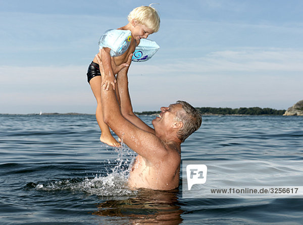Großvater spielt mit dem Jungen im Wasser