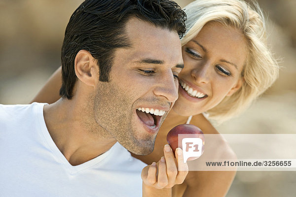 Ein Weibchen füttert einen lateinischen Mann mit einem Apfel.