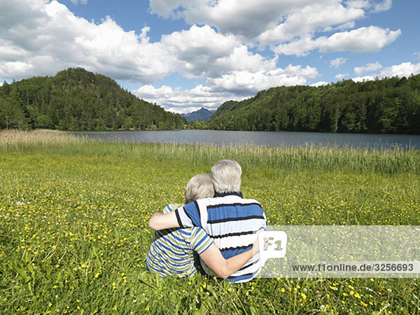 Seniorenpaar im Feld am See sitzend