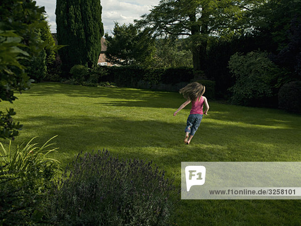 A young girl running in a garden