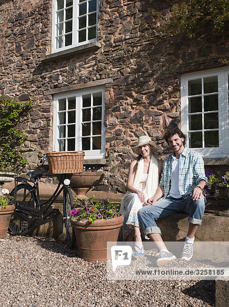 Man and woman sit outside country house