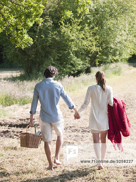 Couple walking in field with picnic