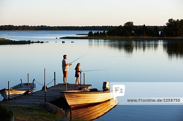 Father and daughter fishing from a jetty  Sweden.