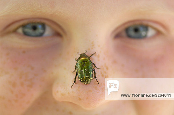 Eine Mädchen mit ein Käfer auf ihr Nase  Nahaufnahme.