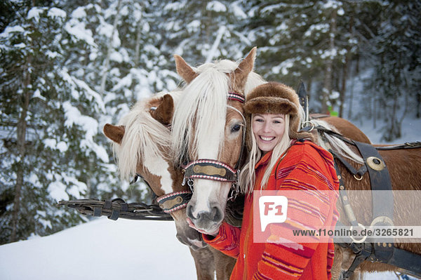 Österreich  Salzburger Land  Junge Frau neben Pferden stehend  lächelnd  Portrait