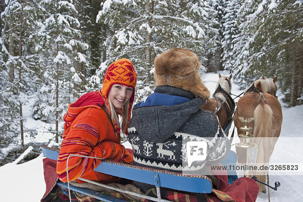 Austria  Salzburger Land  Couple riding in sleigh  smiling  portrait