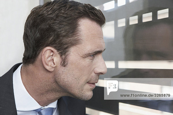Deutschland  Köln  Geschäftsmann durchs Fenster schauen  Seitenansicht  Portrait  Nahaufnahme