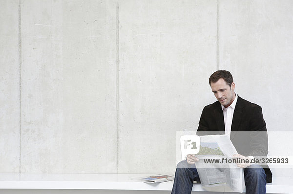 Deutschland,  Köln,  Geschäftsmann auf Bank sitzend Zeitung lesen,  Portrait