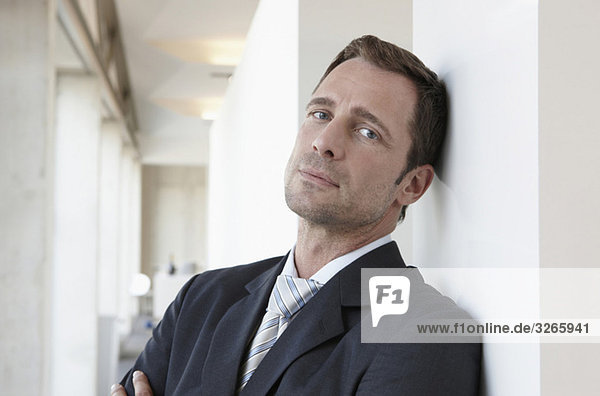 Germany  Cologne  Businessman in corridor  leaning against wall  portrait  close-up