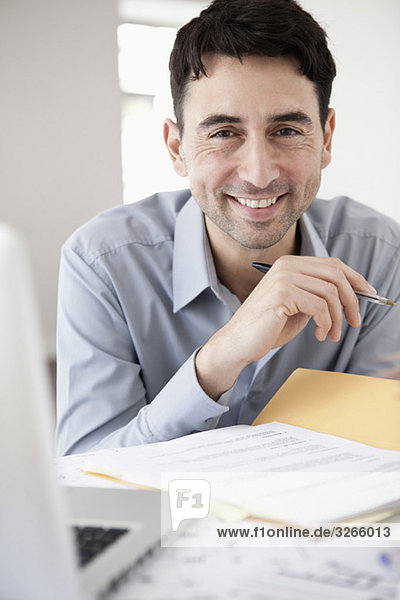 Businessman in office holding ballpen  smiling  portrait
