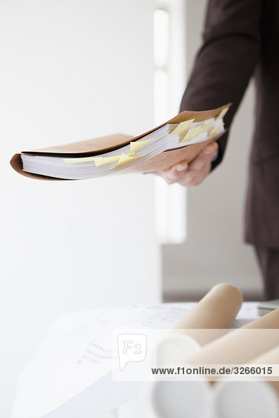 Businessman in office holding documents  mid section