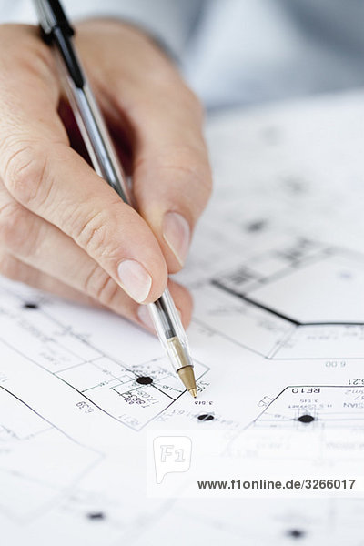 Architect pointing at blueprint with pen  close-up of hand
