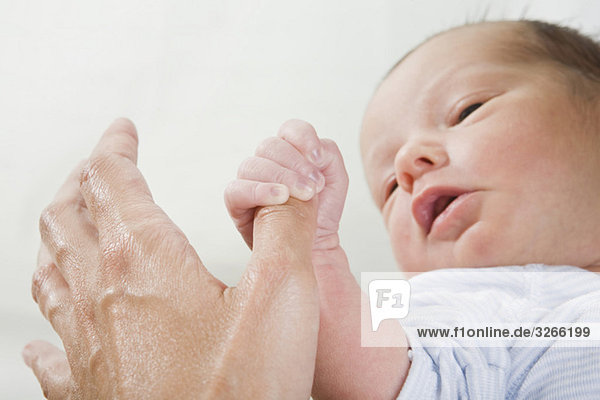 Kleines Mädchen (0-4 Wochen) mit der Hand des Vaters