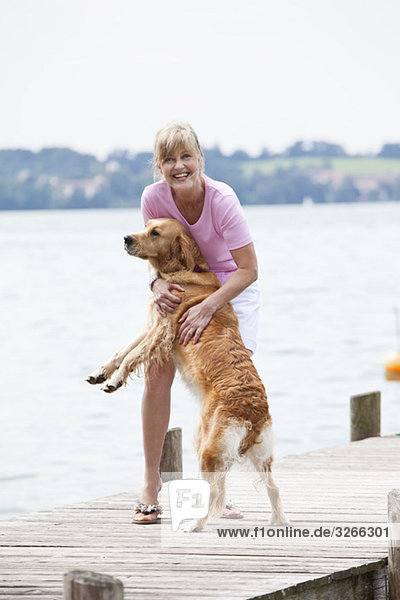 Starnberger See  Senior woman with Golden Retriever on jetty