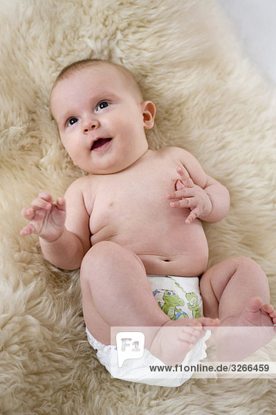 Junge (6-11 Monate) auf Fell liegend  erhöhte Ansicht