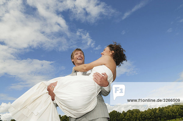 Germany  Bavaria  Groom lifting bride  laughing  portrait