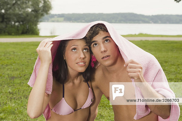 Deutschland  Bayern  Starnberger See  Junges Paar mit Handtuch über dem Kopf  Portrait  Nahaufnahme
