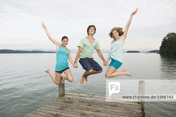 Germany  Bavaria  Starnberger See  Young people jumping on jetty  laughing  portrait