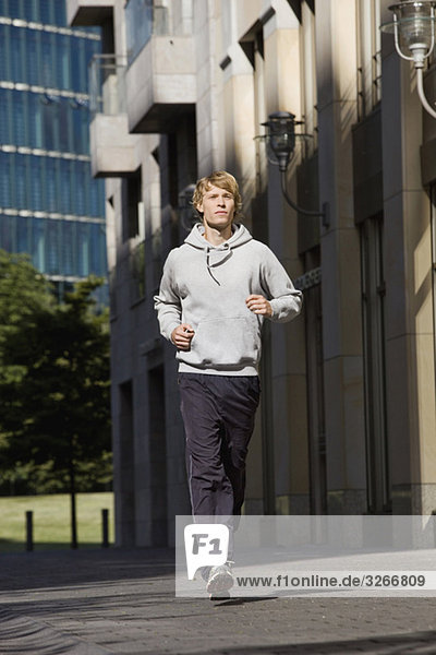 Young man jogging in street  buildings in background
