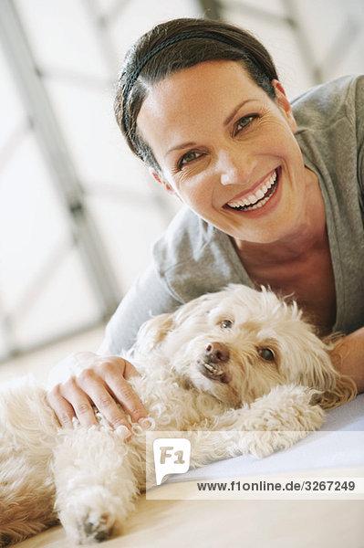 Frau auf dem Boden liegend mit Hund neben ihr  lächelnd  Portrait