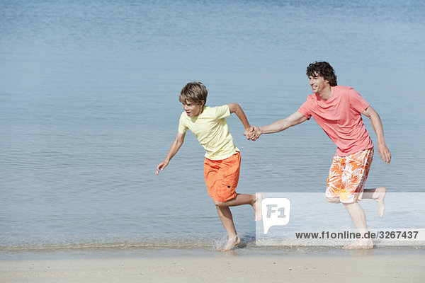 Spain  Mallorca  Father and son (8-9) running across on beach