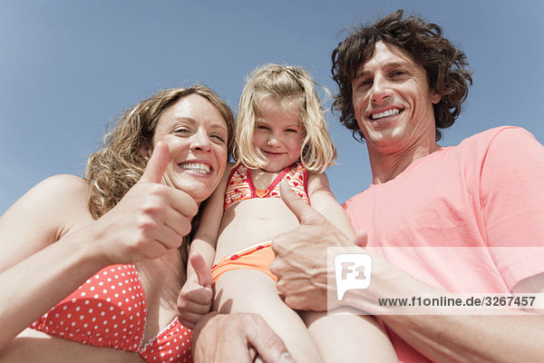 Spanien  Mallorca  Familie am Strand Daumen hoch  lachend  Portrait