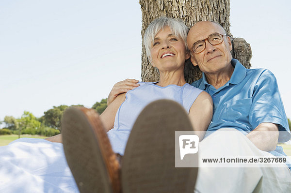 Spanien  Mallorca  Seniorenpaar am Baum sitzend  entspannend