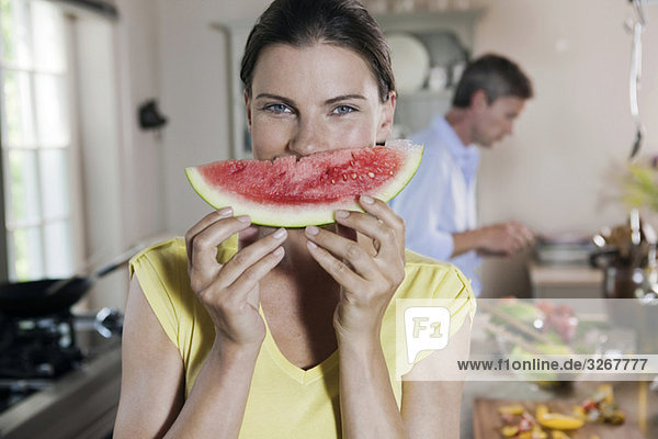 Couple in kitchen  woman holding melon slice