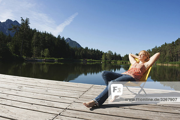 Italy  South Tyrol  Woman sunbathing on jetty by lake