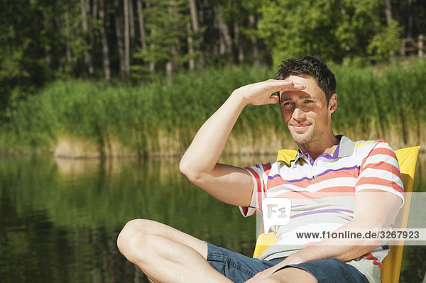 Italy  South Tyrol  Man sitting in chair by lake  portrait