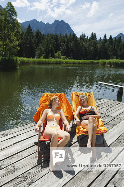 Italy  South Tyrol  Women sitting in deck chair on jetty  smiling  portrait