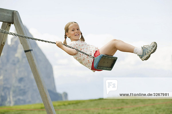 Italy  Seiseralm  Girl (6-7) sitting on swing  portrait