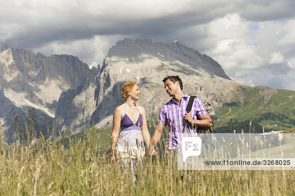 Italy  Seiseralm  Couple walking hand in hand in meadow
