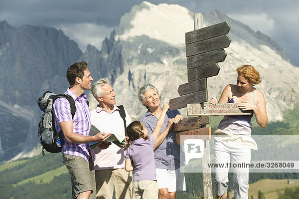 Italy  Seiseralm  Girl (6-7) with family looking at sign post  smiling