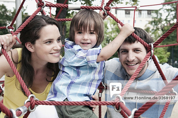 Deutschland  Berlin  Eltern mit Sohn (2-3) im Klettergerüst  lächelnd
