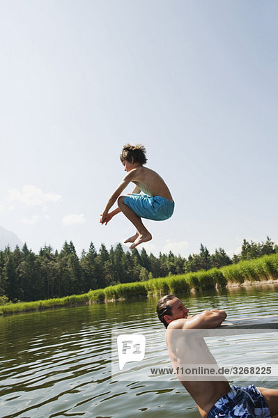 Italien Südtirol  Vater und Sohn (10-11)  Sohn springt in den See