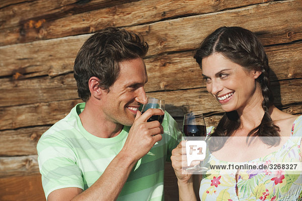 Italien  Südtirol  Paar vor dem Blockhaus mit Weingläsern  lächelnd  Portrait